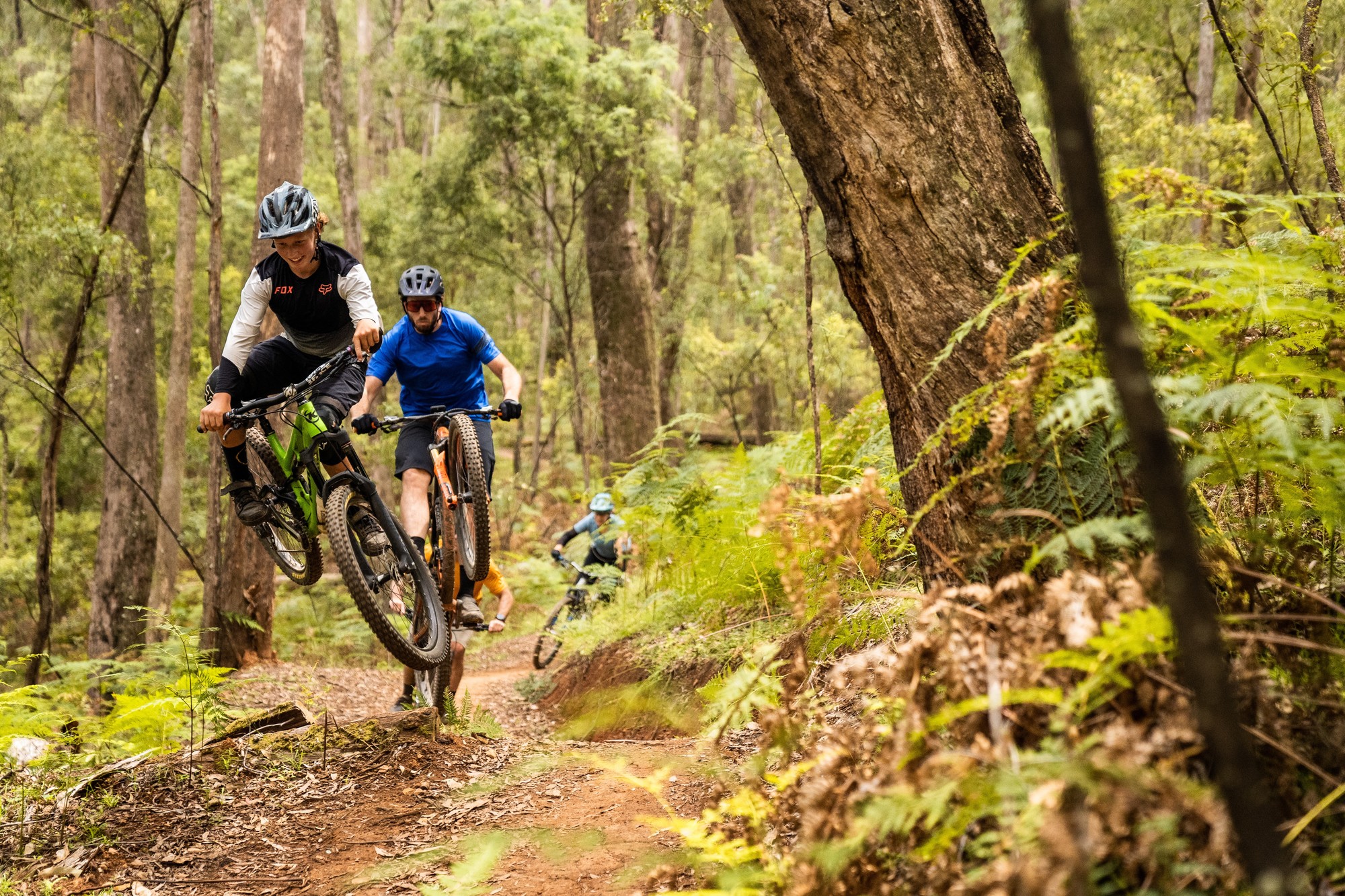 Group of cyclists jumping mountain biking features on the Indigo Epic trail